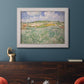 Impressionist countryside landscape near Auvers by Vincent van Gogh in an ornate weathered white frame displayed in a dark-toned interior setting.