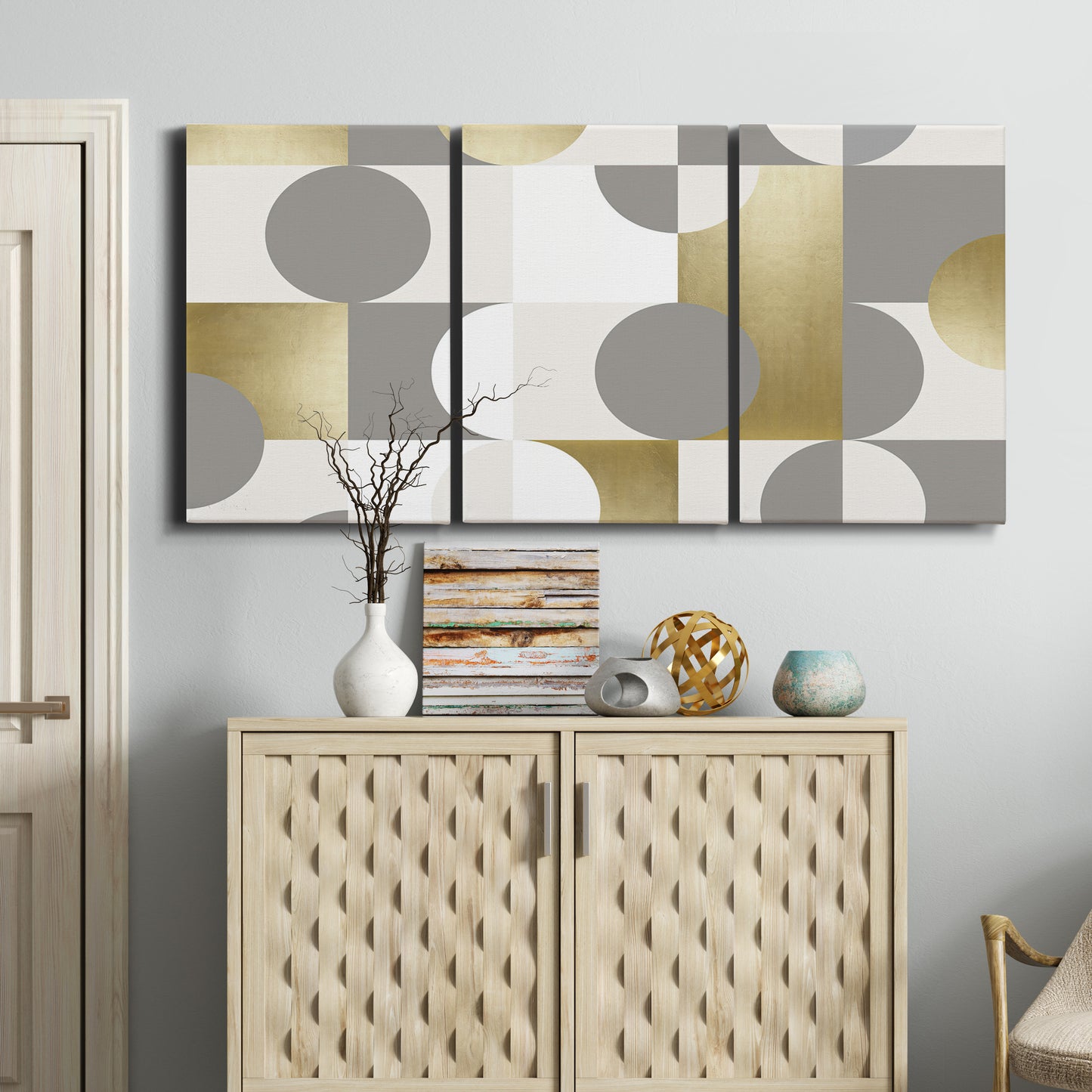 Three-panel canvas wall art featuring geometric gold abstract reflections, displayed above a cabinet in an entryway.