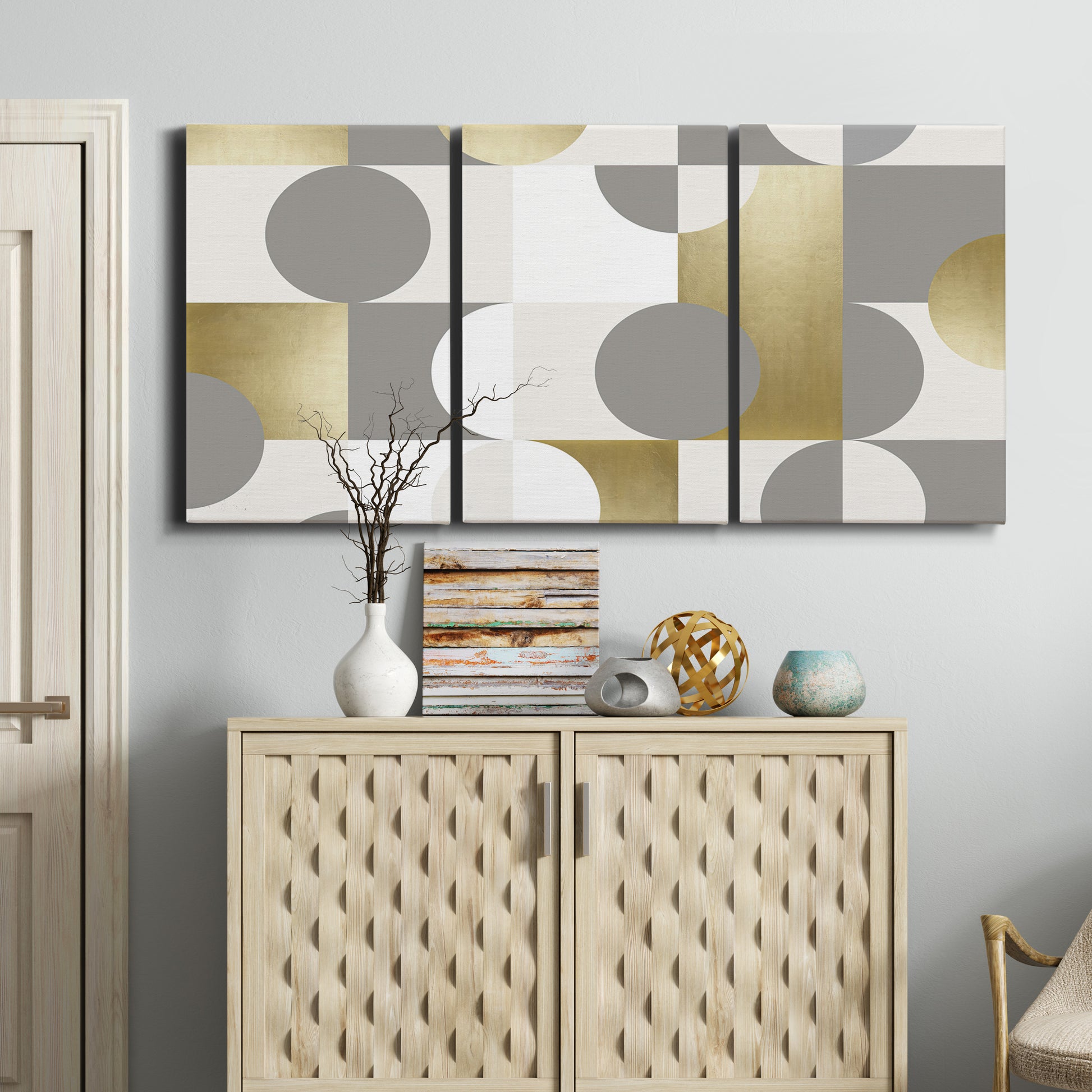 Three-panel canvas wall art featuring geometric gold abstract reflections, displayed above a cabinet in an entryway.