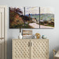 Three-panel canvas wall art featuring country road through village, displayed above a cabinet in an entryway.