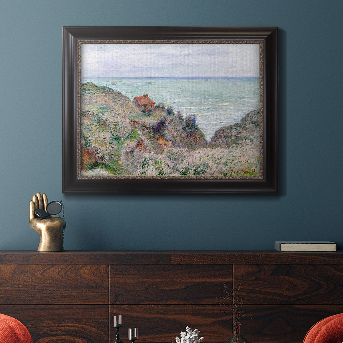 Impressionist coastal watch cabin scene by Claude Monet in an ornate black frame with gilded inner detail displayed in a dark-toned interior setting.