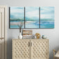 Three-panel canvas wall art featuring sunset silhouette over coastal water, displayed above a cabinet in an entryway.