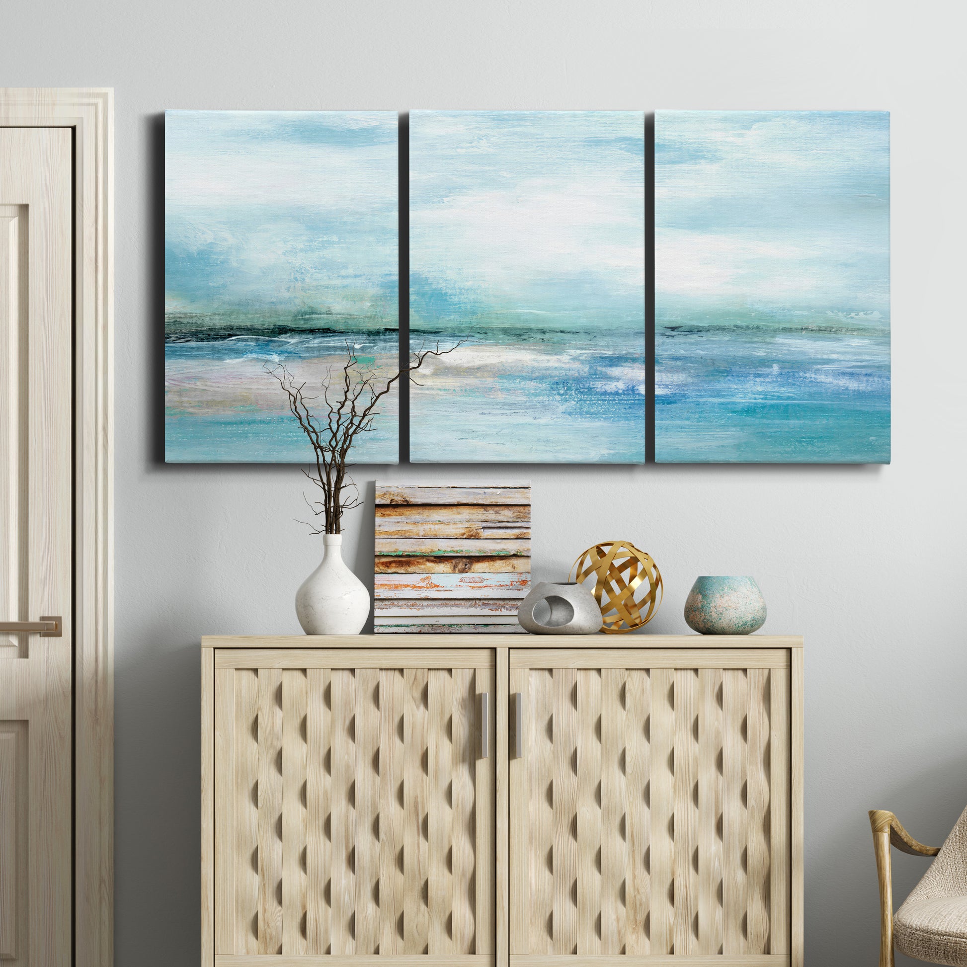 Three-panel canvas wall art featuring sunset silhouette over coastal water, displayed above a cabinet in an entryway.