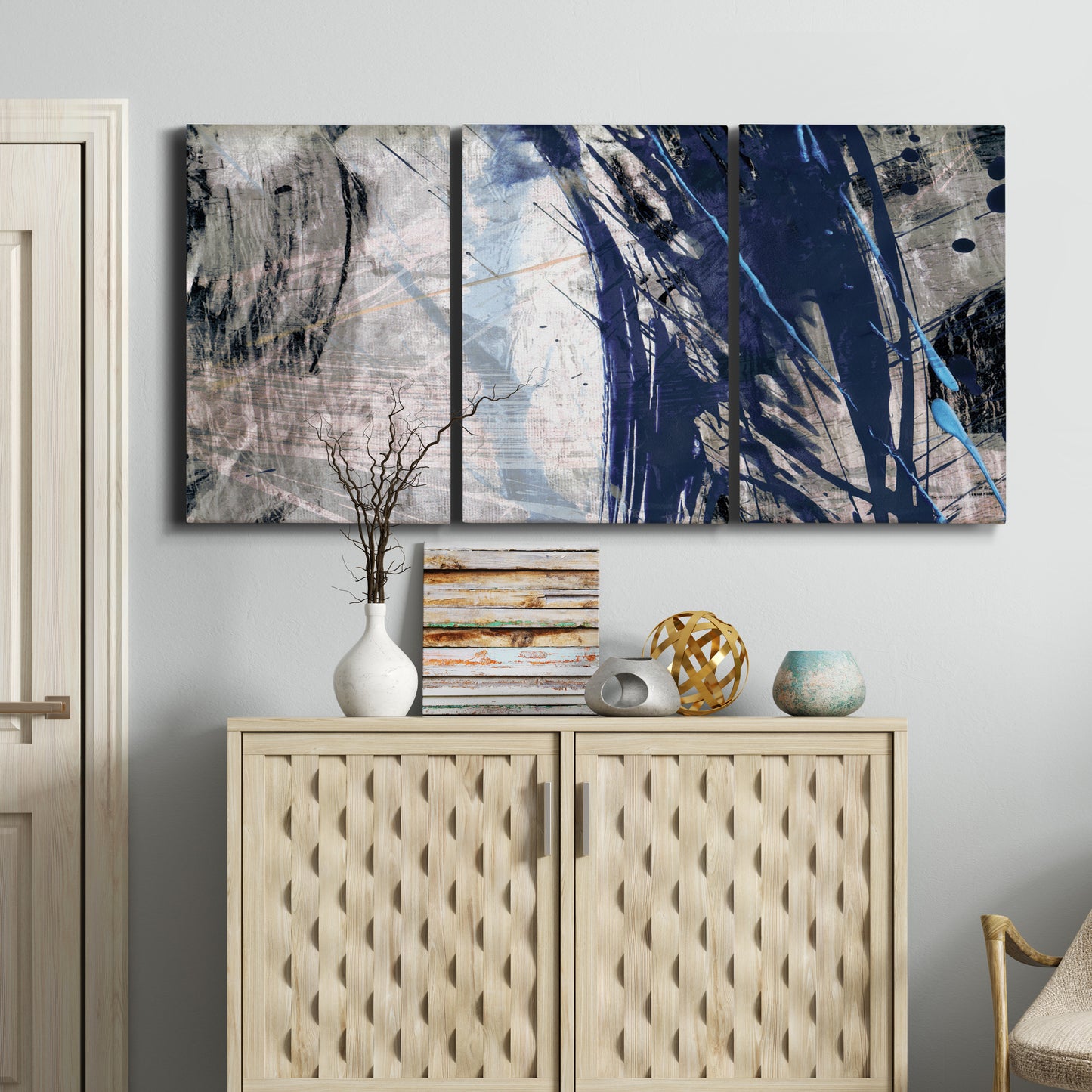 Three-panel canvas wall art featuring layered blue abstract texture, displayed above a cabinet in an entryway.