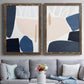 Set of two walnut barnwood framed canvas prints depicting paired minimalist color-block abstracts with rounded dark forms, pale sand fields, and clean modern edges above a sofa in a contemporary living room.