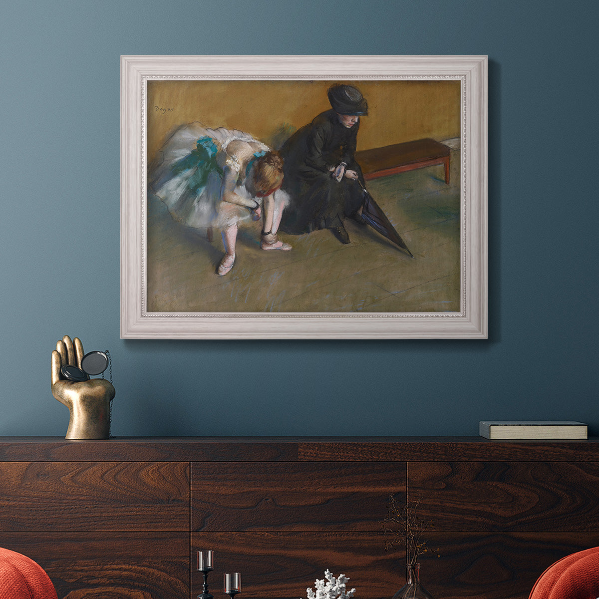 Impressionist portrait of a seated woman by Edgar Degas in an ornate weathered white frame displayed in a dark-toned interior setting.