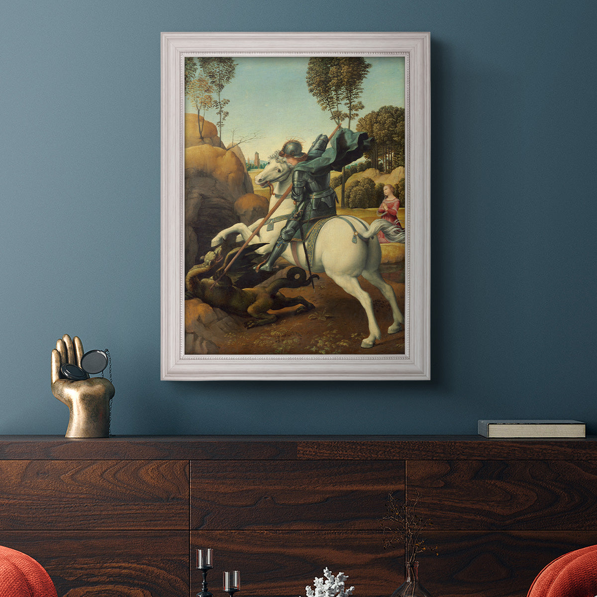 Religious painting of Saint George slaying the dragon by Raphael in an ornate weathered white frame displayed in a dark-toned interior setting.