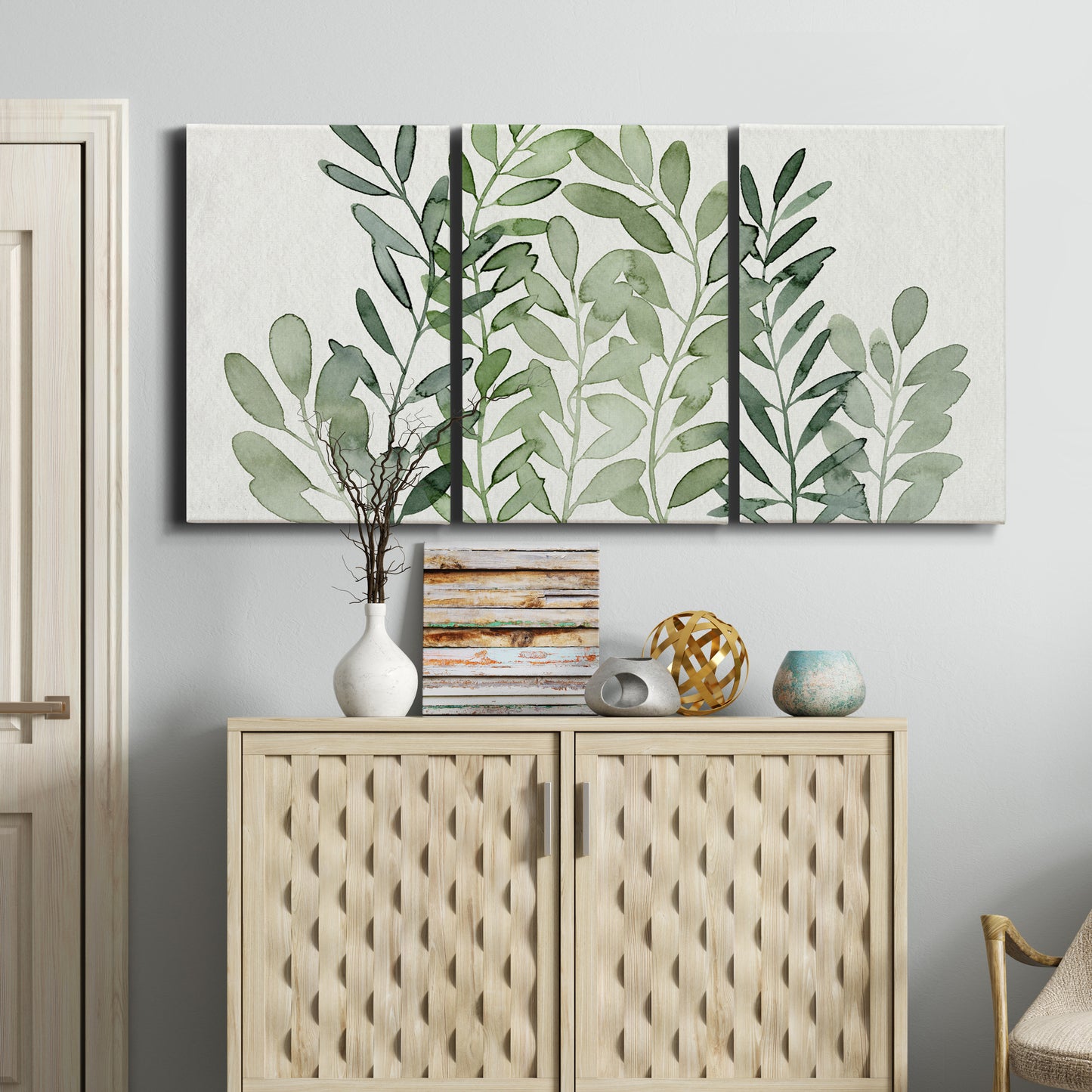 Three-panel canvas wall art featuring foraged leafy greens botanical study, displayed above a cabinet in an entryway.