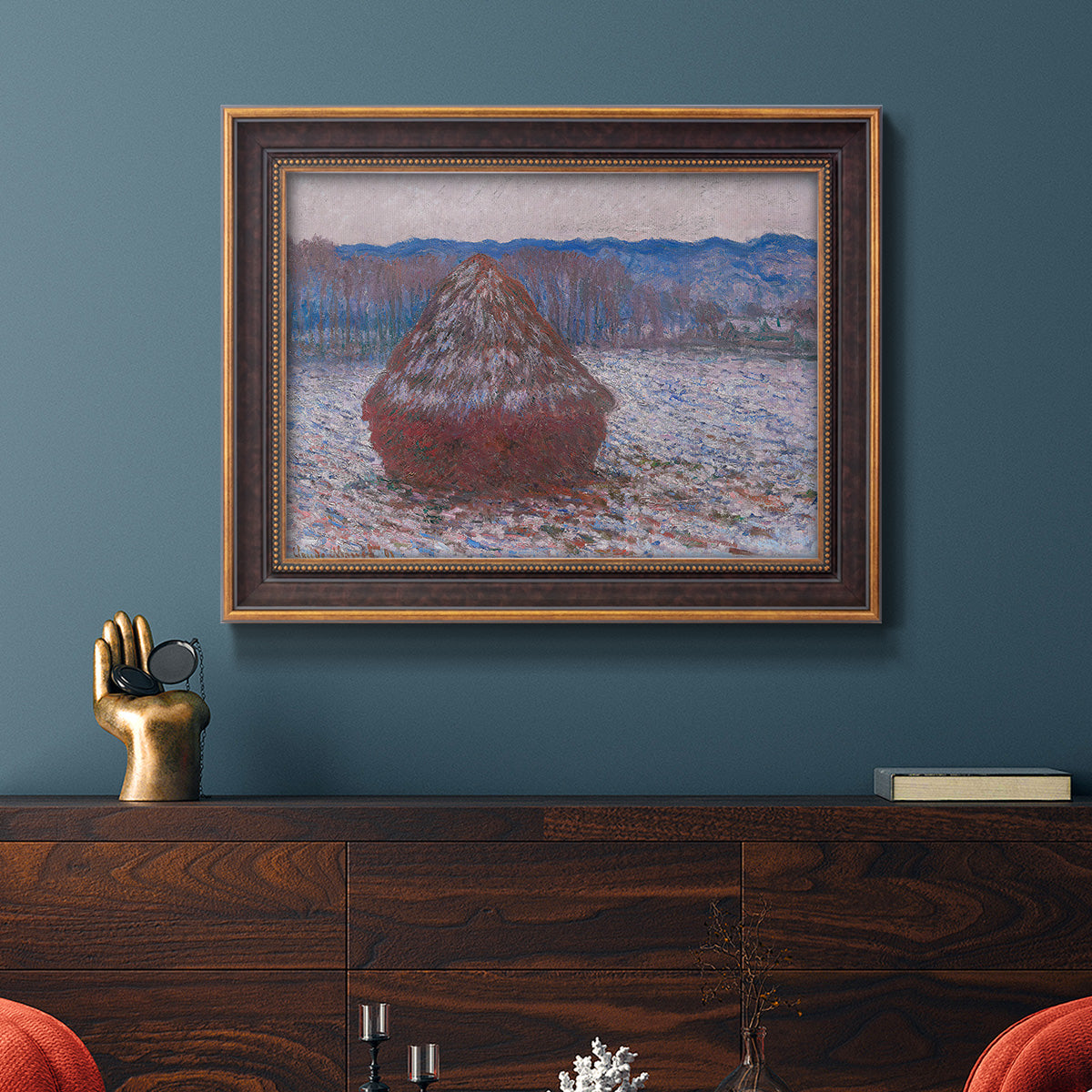 Impressionist single haystack landscape by Claude Monet in an ornate bronzed mahogany wood frame displayed in a dark-toned interior setting.