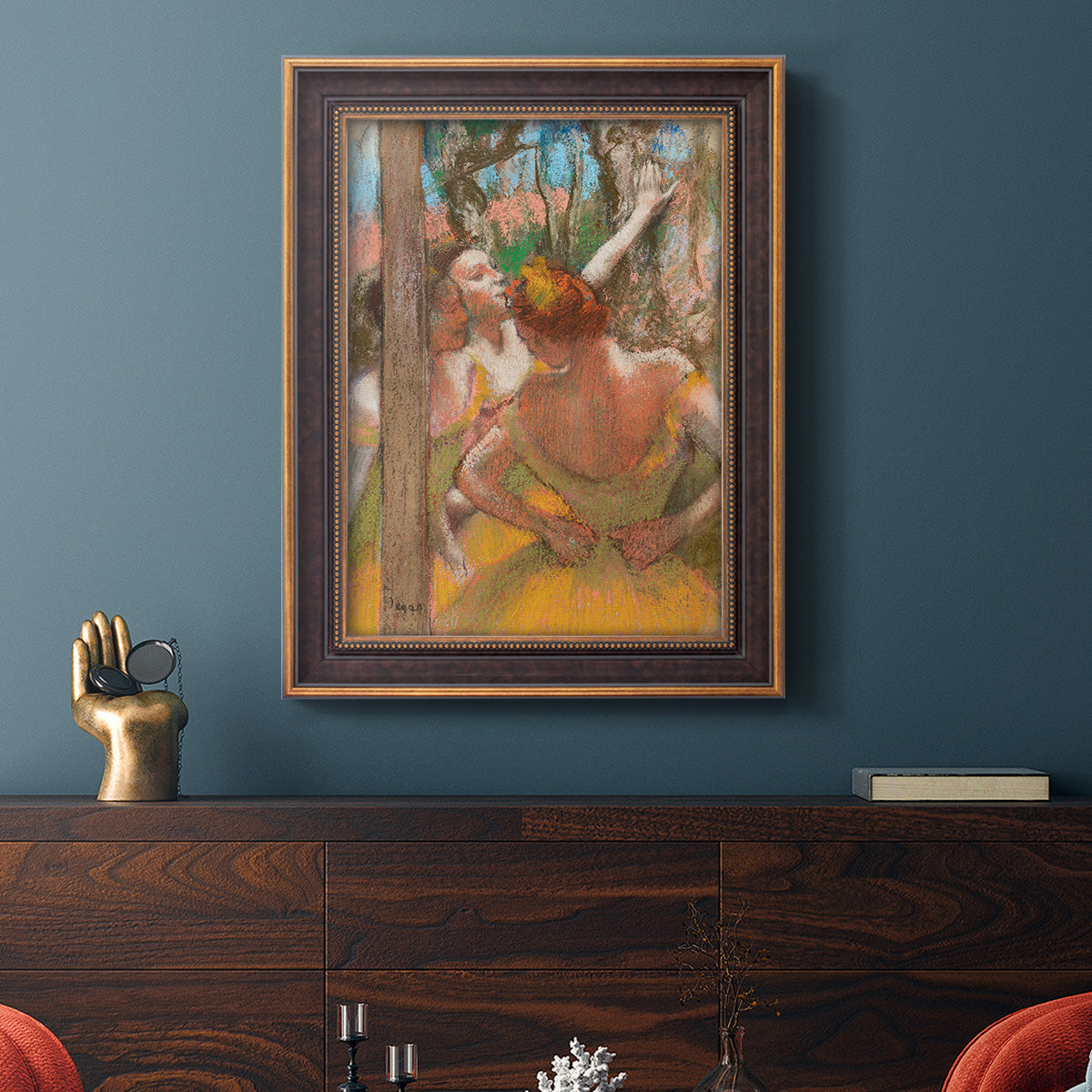 Impressionist ballet dancer composition by Edgar Degas in an ornate bronzed mahogany wood frame displayed in a dark-toned interior setting.