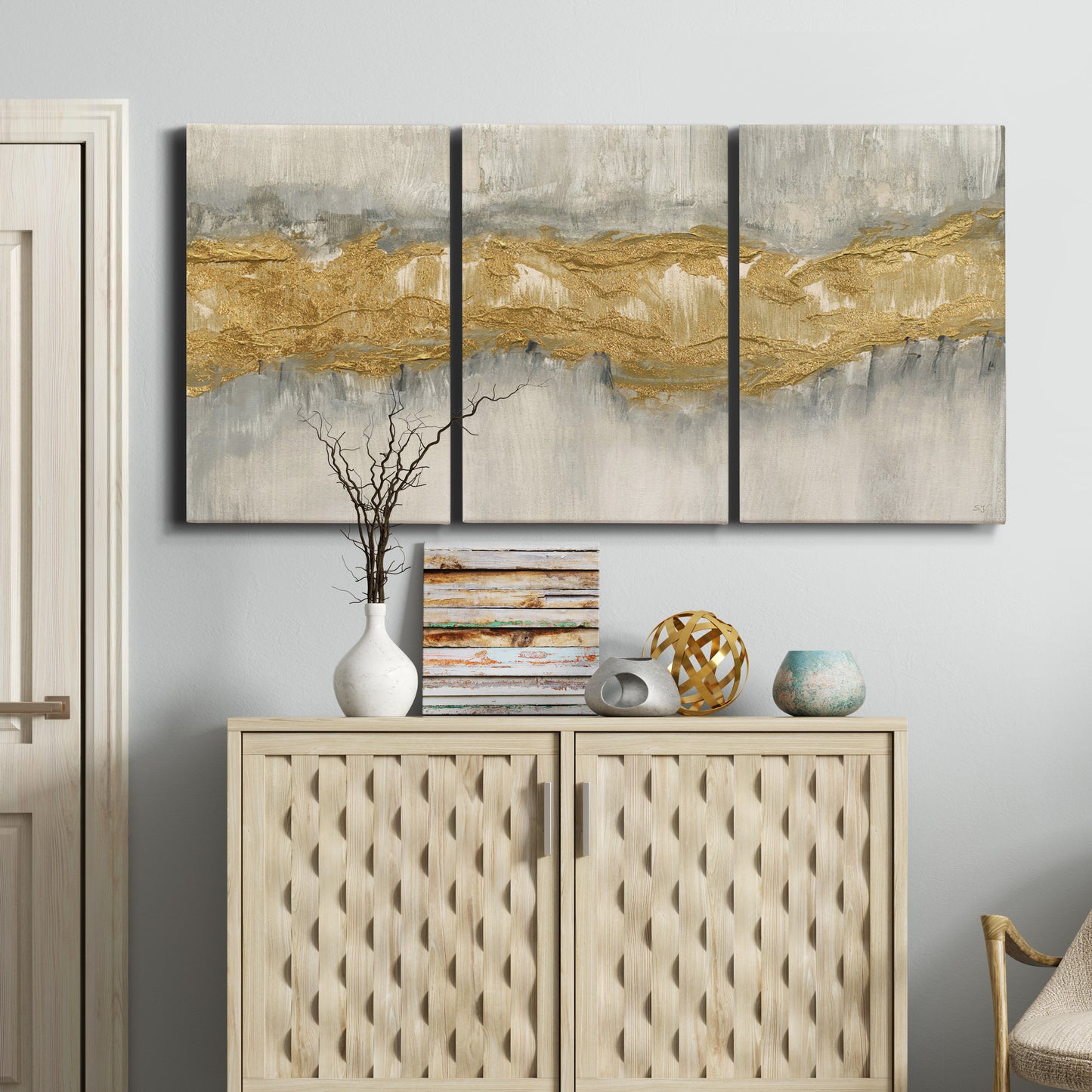 Three-panel canvas wall art featuring flowing abstract golden tones, displayed above a cabinet in an entryway.