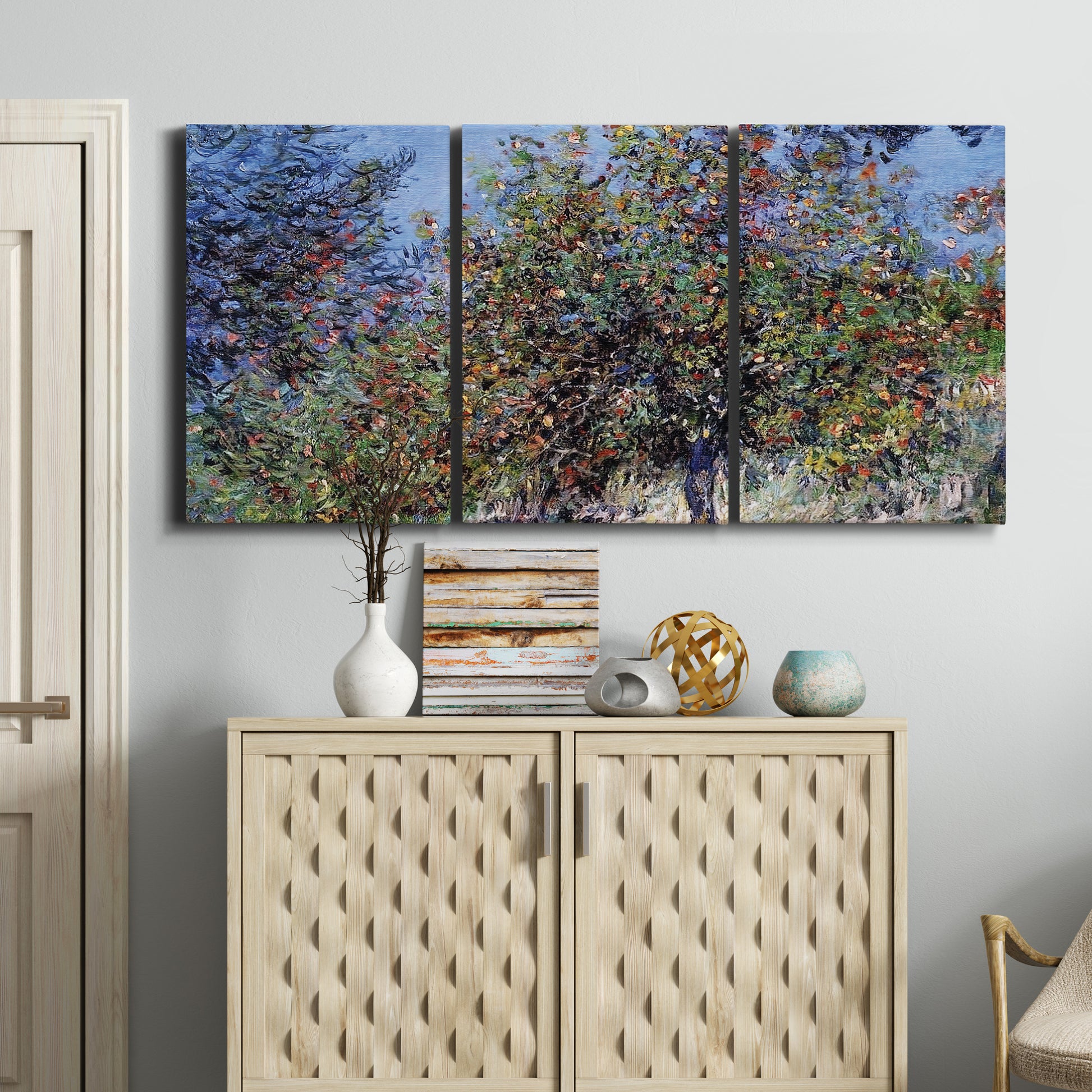 Three-panel canvas wall art featuring orchard of trees in spring bloom, displayed above a cabinet in an entryway.