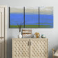 Three-panel canvas wall art featuring abstract coastal inlet landscape, displayed above a cabinet in an entryway.