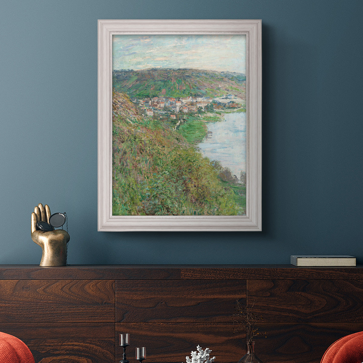 Impressionist landscape view of Vétheuil by Claude Monet in an ornate weathered white frame displayed in a dark-toned interior setting.