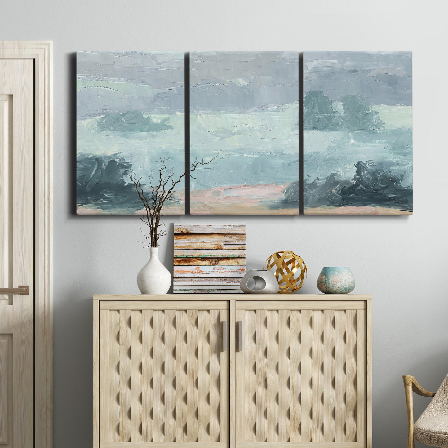 Three-panel canvas wall art featuring soft pastel valley landscape, displayed above a cabinet in an entryway.