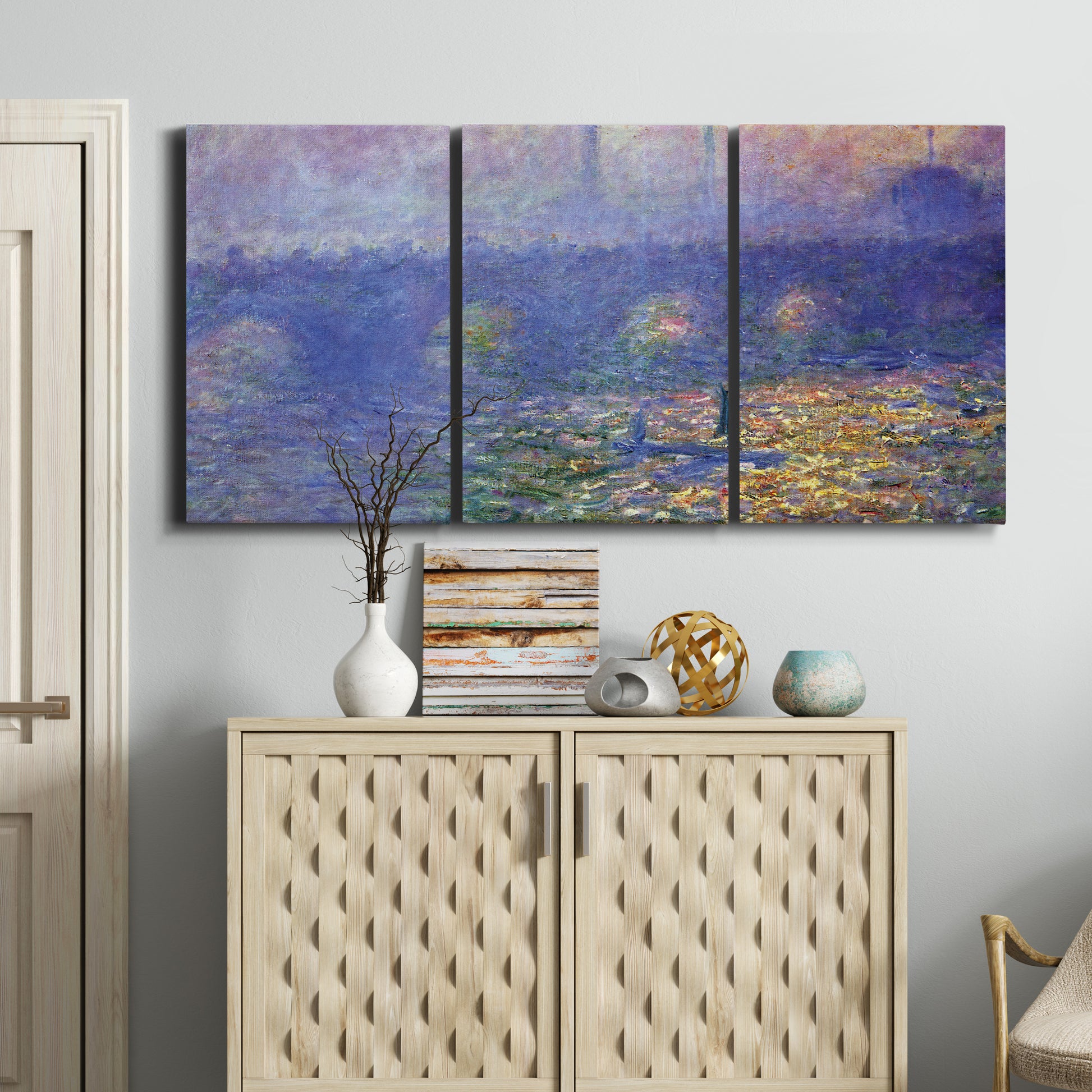 Three-panel canvas wall art featuring overcast bridge above river, displayed above a cabinet in an entryway.