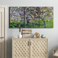 Three-panel canvas wall art featuring apple trees blooming beside water, displayed above a cabinet in an entryway.