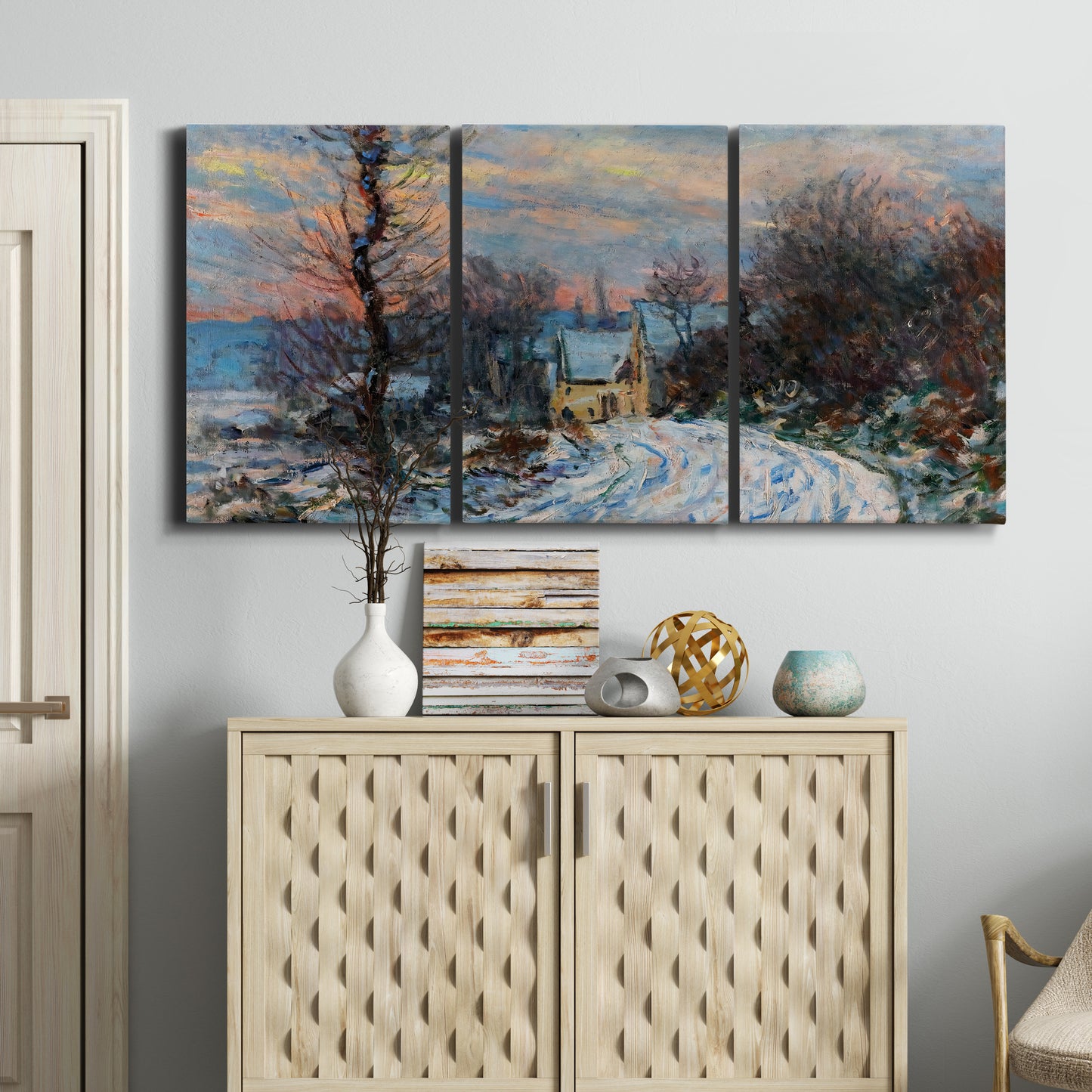 Three-panel canvas wall art featuring snow covered road leading to village, displayed above a cabinet in an entryway.