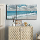 Three-panel canvas wall art featuring tropical beach scene with turquoise water, displayed above a cabinet in an entryway.