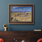 Impressionist wheat harvest scene by Vincent van Gogh in an ornate bronzed mahogany wood frame displayed in a dark-toned interior setting.