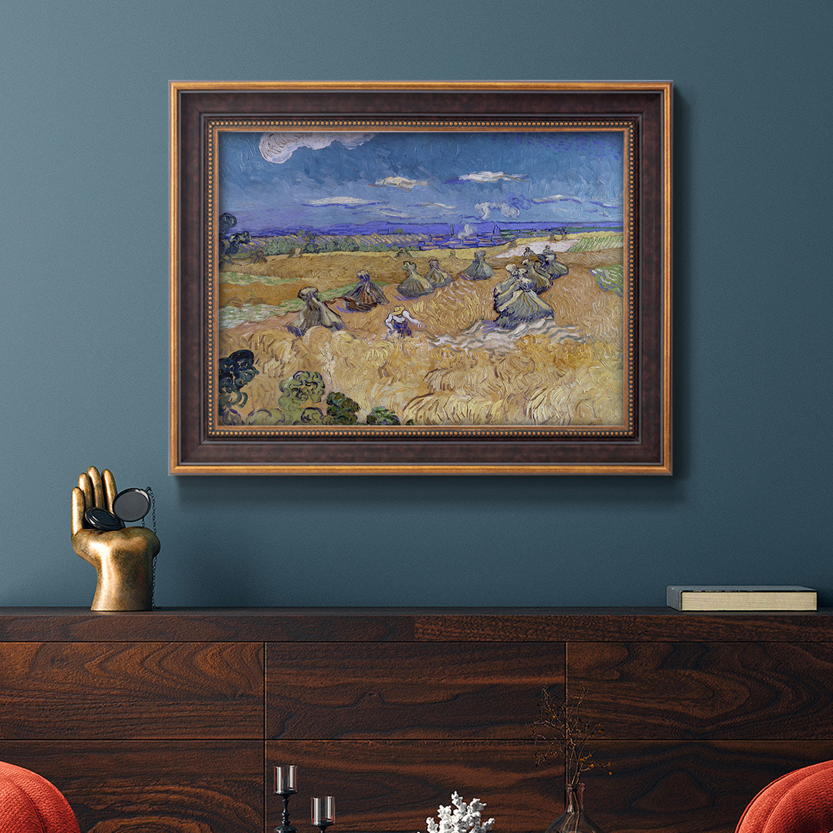 Impressionist wheat harvest scene by Vincent van Gogh in an ornate bronzed mahogany wood frame displayed in a dark-toned interior setting.