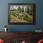 Impressionist countryside harvest scene by Camille Pissarro in an ornate black frame with gilded inner detail displayed in a dark-toned interior setting.