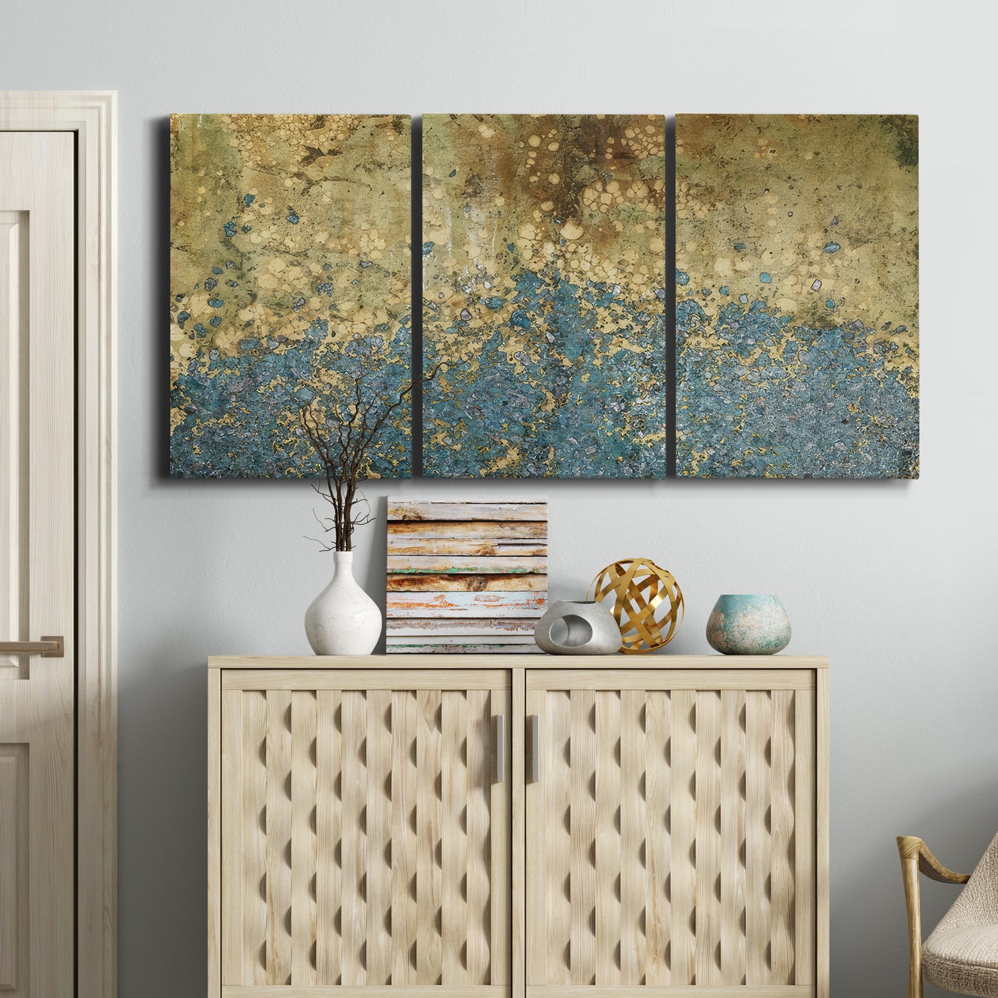 Three-panel canvas wall art featuring metallic abstract gold tones, displayed above a cabinet in an entryway.