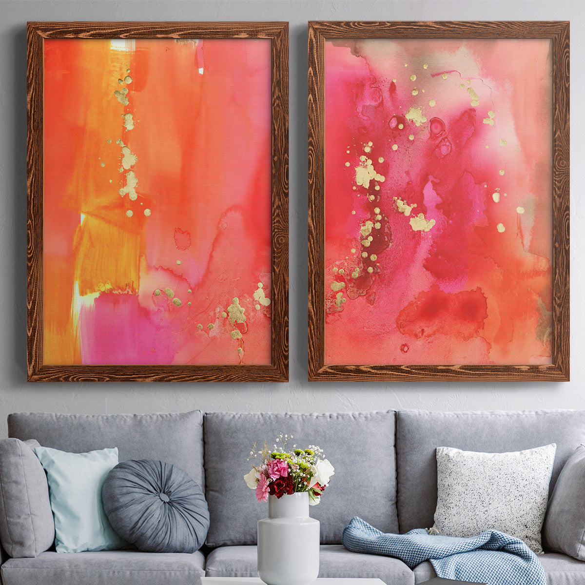 Set of two maple barnwood framed canvas prints depicting paired glamorous fluid abstracts with translucent warm washes, drips, and scattered metallic accents above a sofa in a contemporary living room.
