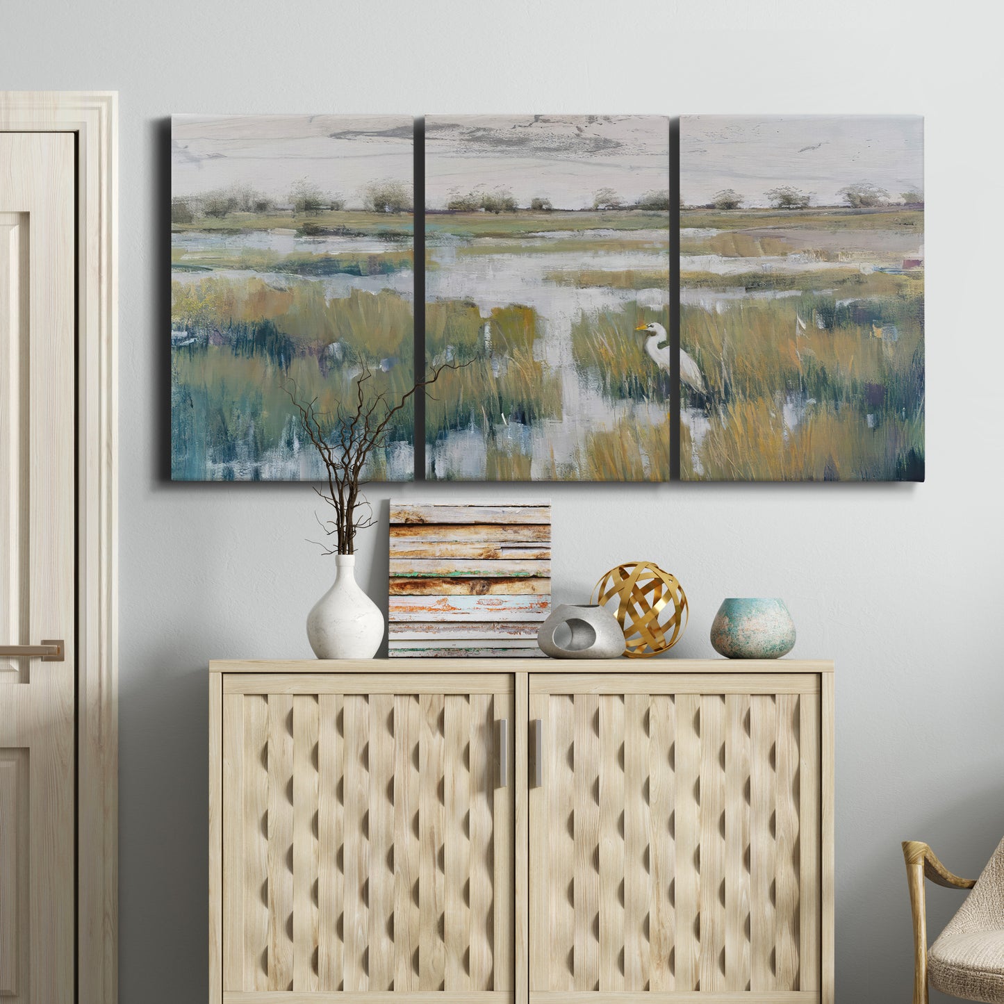 Three-panel canvas wall art featuring pastoral marshland landscape, displayed above a cabinet in an entryway.