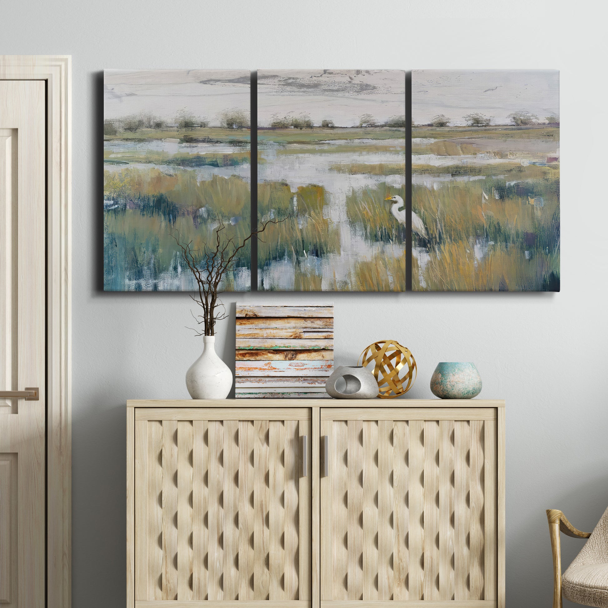 Three-panel canvas wall art featuring pastoral marshland landscape, displayed above a cabinet in an entryway.