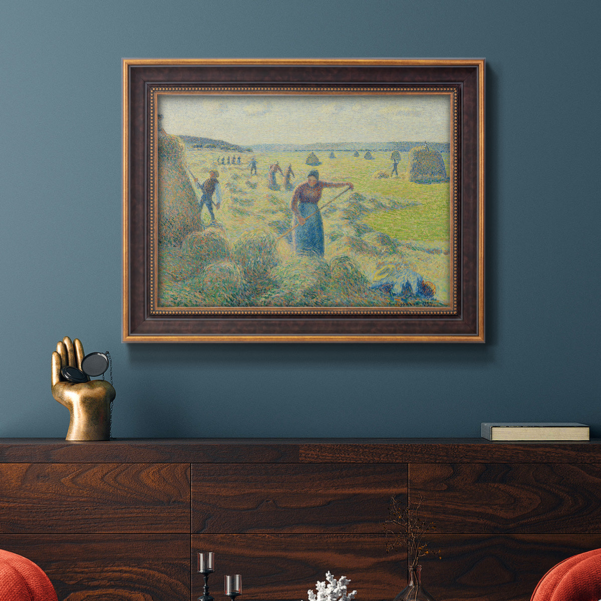 Impressionist rural hay harvest landscape by Camille Pissarro in an ornate bronzed mahogany wood frame displayed in a dark-toned interior setting.