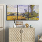Three-panel canvas wall art featuring river village landscape with hills, displayed above a cabinet in an entryway.