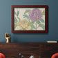 Contemporary peony flower illustration in an ornate cherry burl wood frame displayed in a dark-toned interior setting.