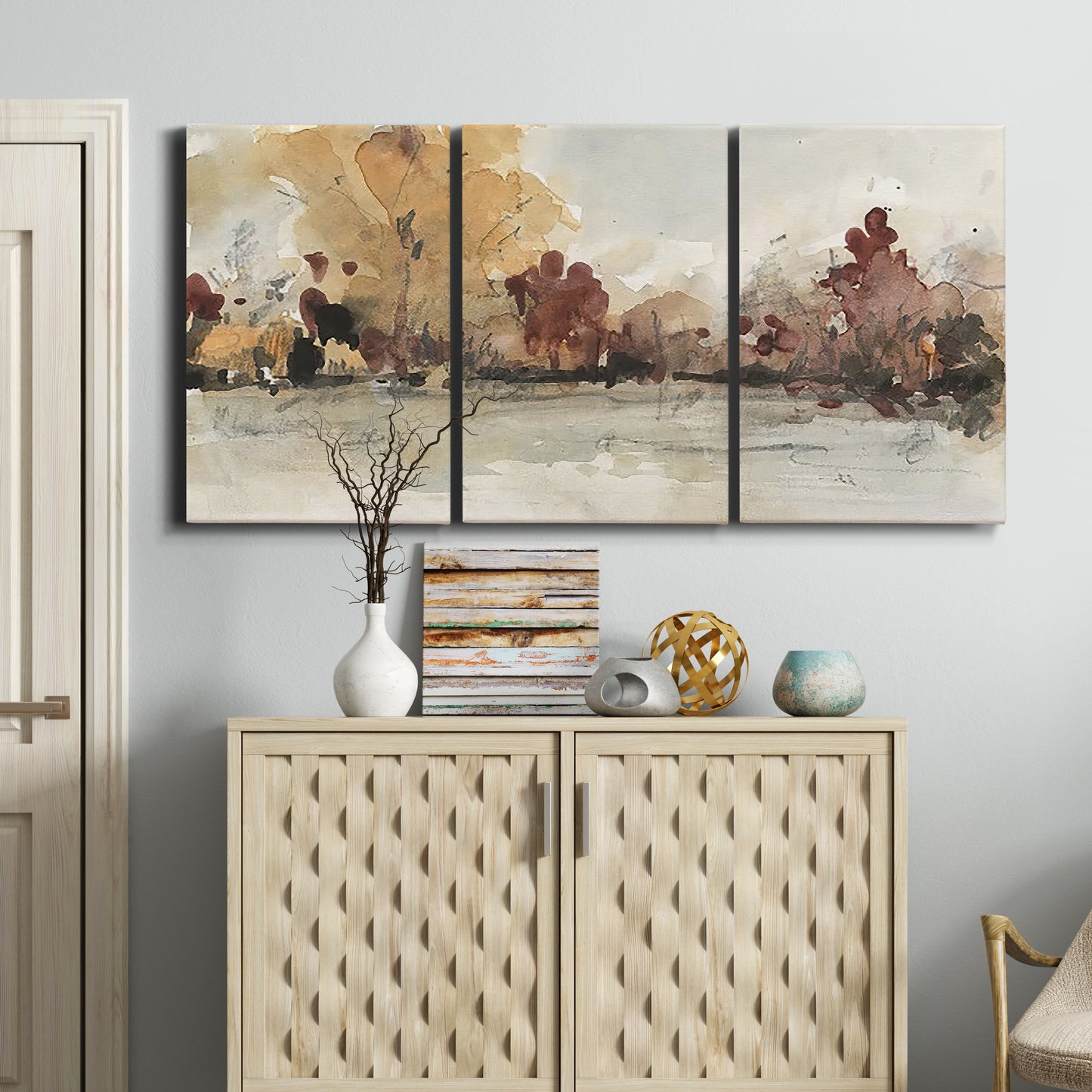Three-panel canvas wall art featuring autumn landscape with trees and field, displayed above a cabinet in an entryway.