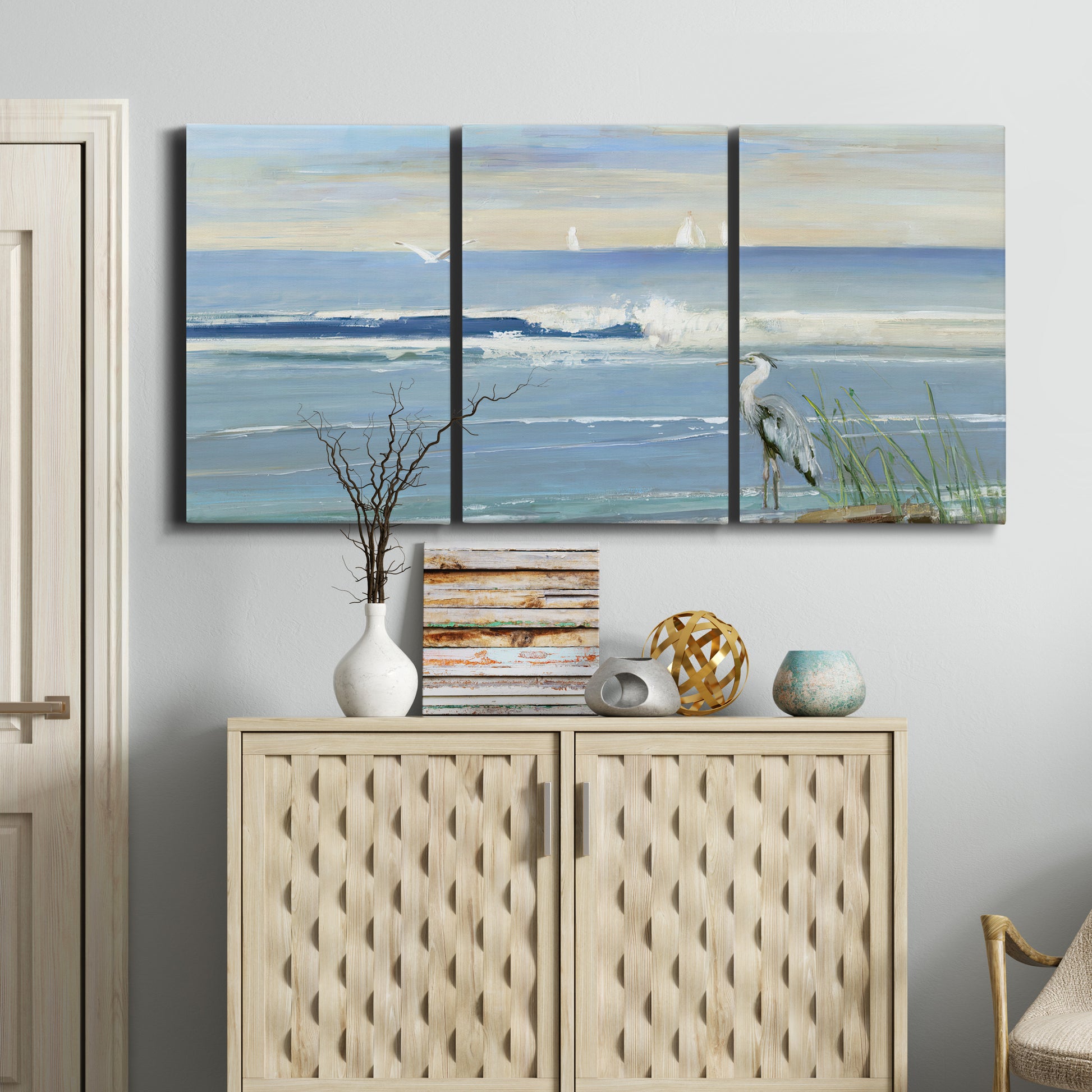 Three-panel canvas wall art featuring sunrise reflecting across bay waters, displayed above a cabinet in an entryway.