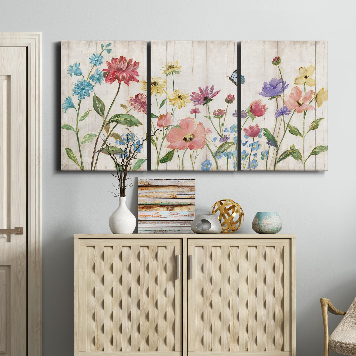 Three-panel canvas wall art featuring delicate wildflower illustration, displayed above a cabinet in an entryway.