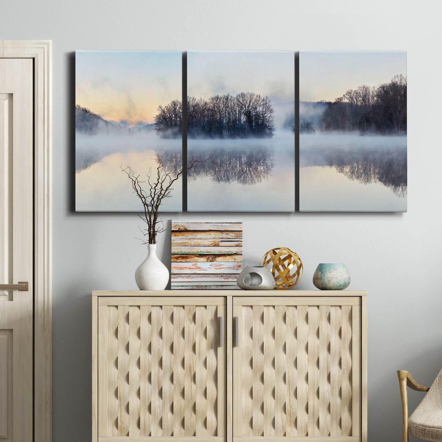 Three-panel canvas wall art featuring misty water landscape photograph, displayed above a cabinet in an entryway.