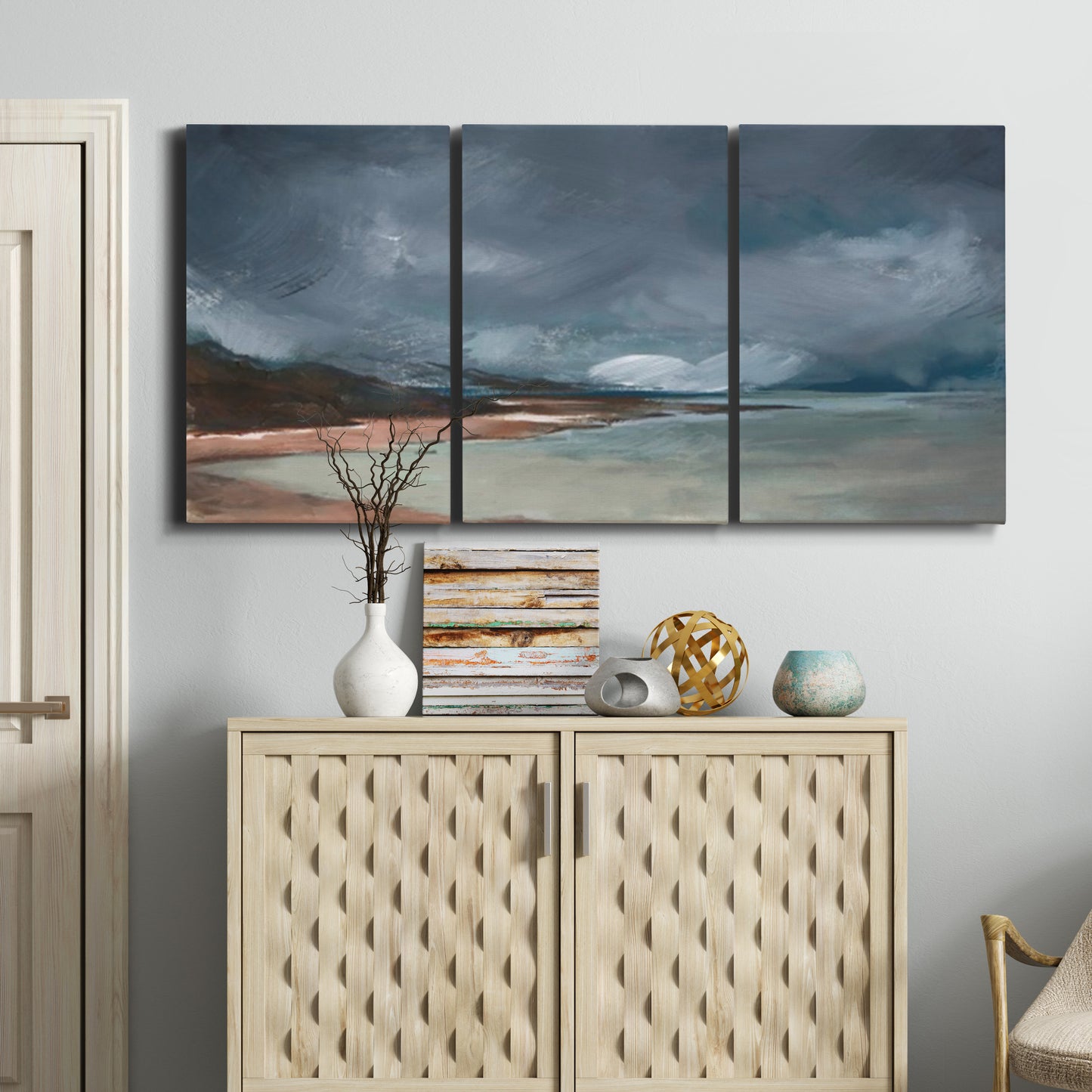 Three-panel canvas wall art featuring stormy sea glass toned coastline, displayed above a cabinet in an entryway.