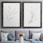 Set of two black barnwood framed canvas prints depicting paired minimalist botanical line drawings with thin gray contours, sparse stems, and clean white fields above a sofa in a contemporary living room.