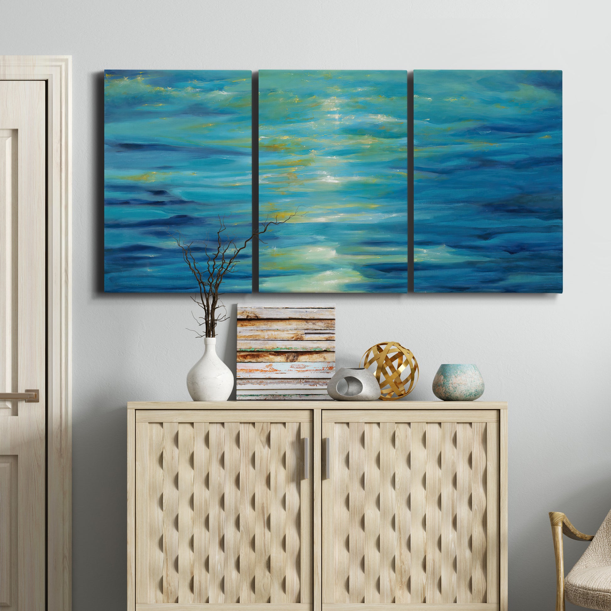 Three-panel canvas wall art featuring deep blue ocean water abstraction, displayed above a cabinet in an entryway.