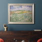 Impressionist countryside landscape near Auvers by Vincent van Gogh in an ornate champagne frame displayed in a dark-toned interior setting.