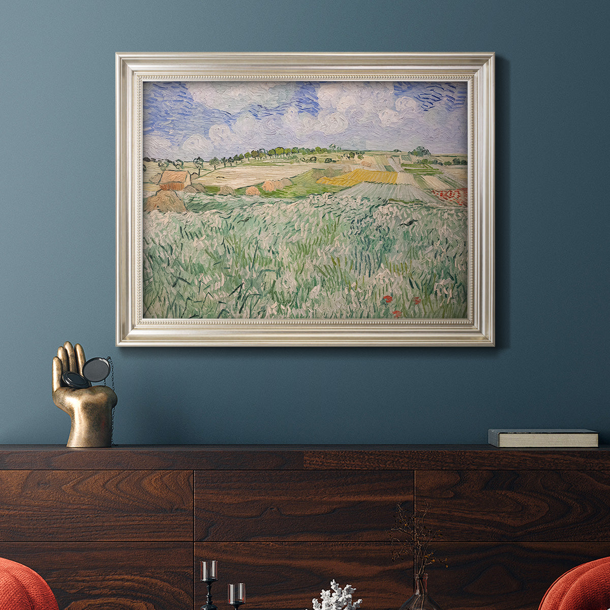 Impressionist countryside landscape near Auvers by Vincent van Gogh in an ornate champagne frame displayed in a dark-toned interior setting.