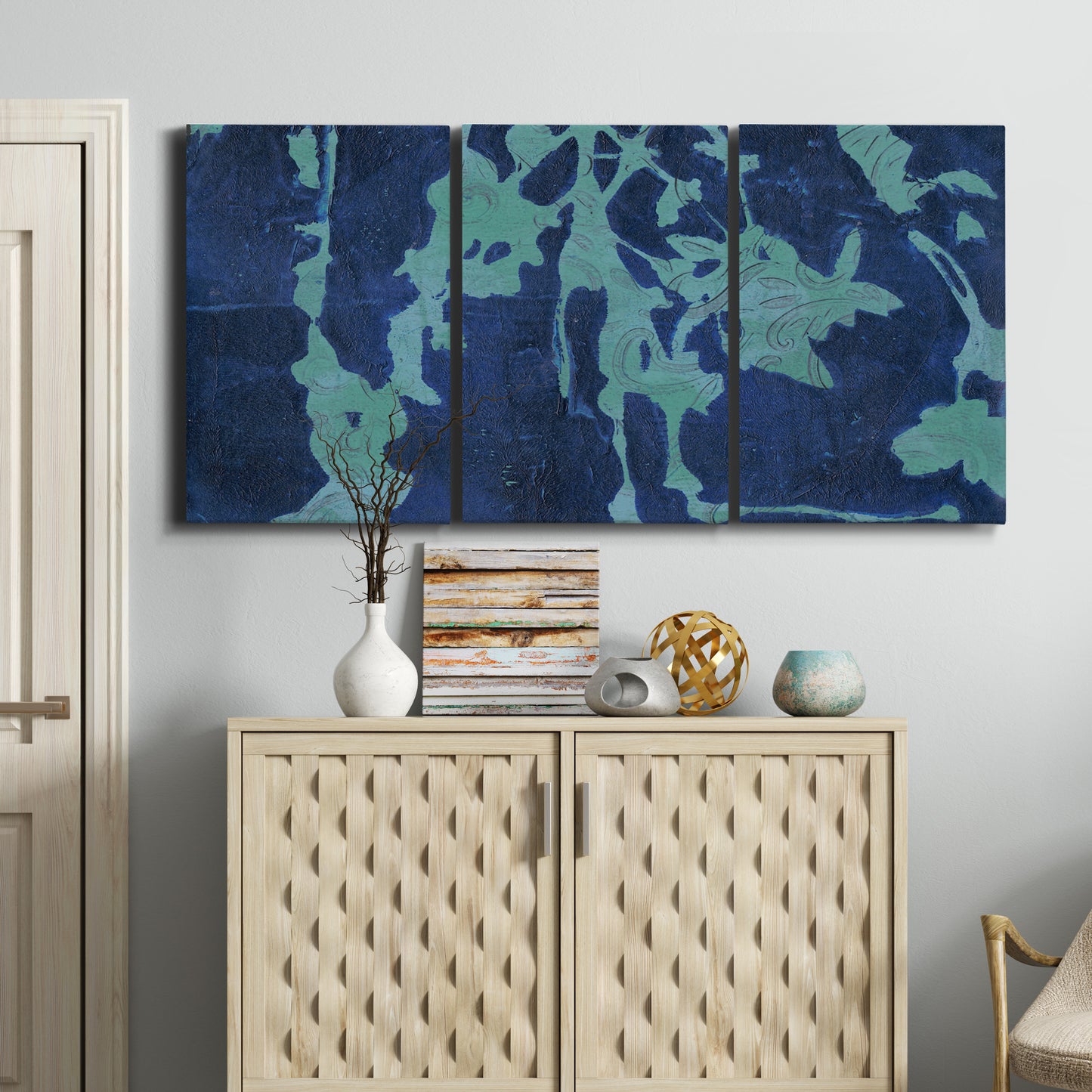 Three-panel canvas wall art featuring abstract floral shapes, displayed above a cabinet in an entryway.