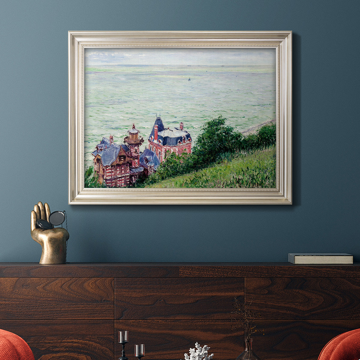 Impressionist coastal villas landscape by Gustave Caillebotte in an ornate champagne frame displayed in a dark-toned interior setting.