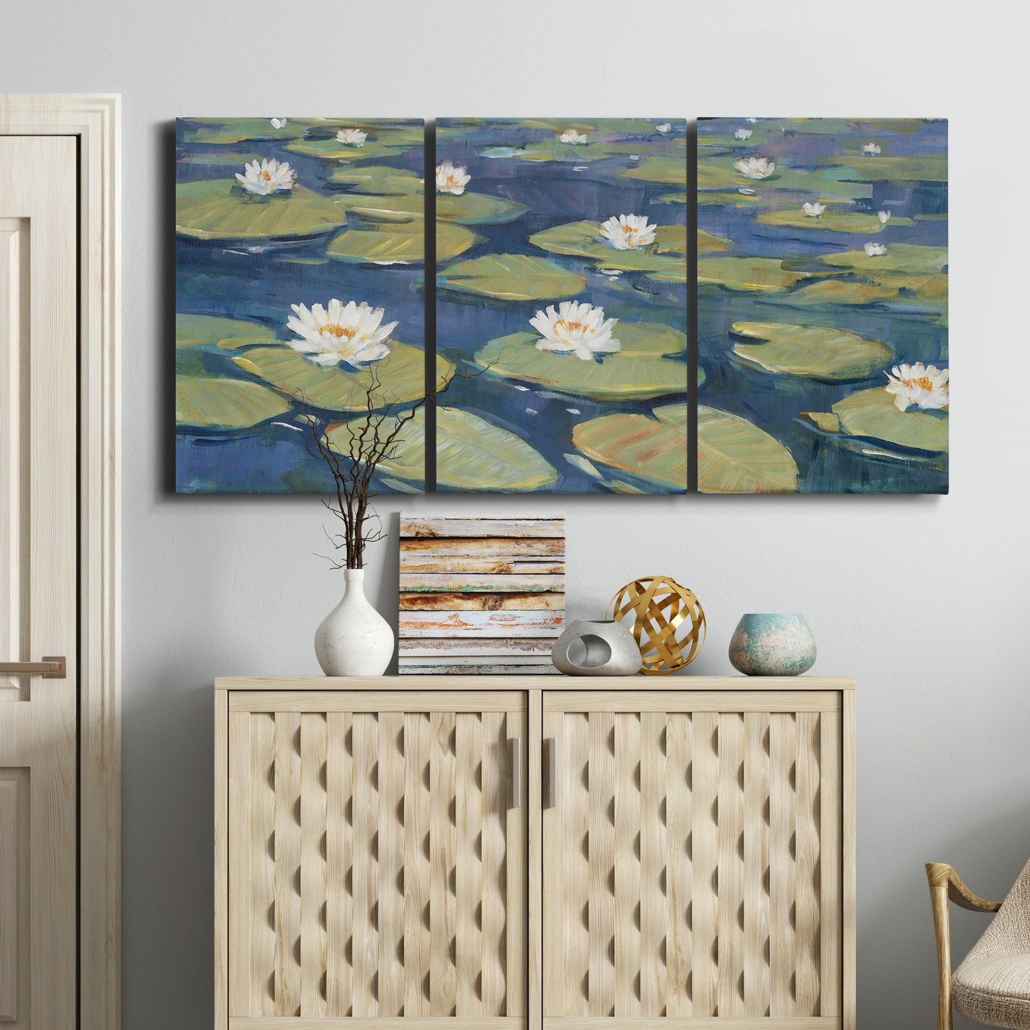 Three-panel canvas wall art featuring water lilies floating on pond, displayed above a cabinet in an entryway.