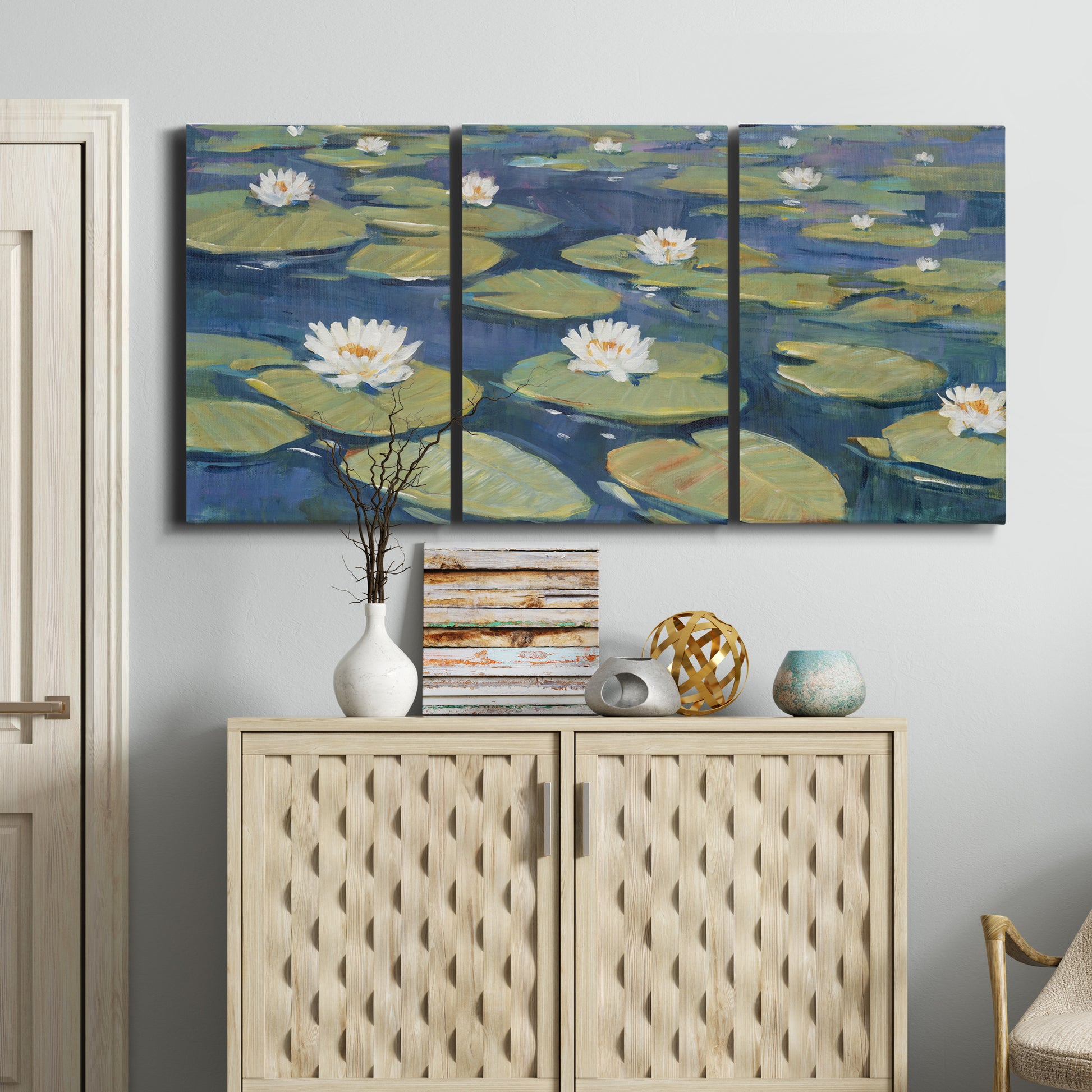 Three-panel canvas wall art featuring water lilies floating on pond, displayed above a cabinet in an entryway.