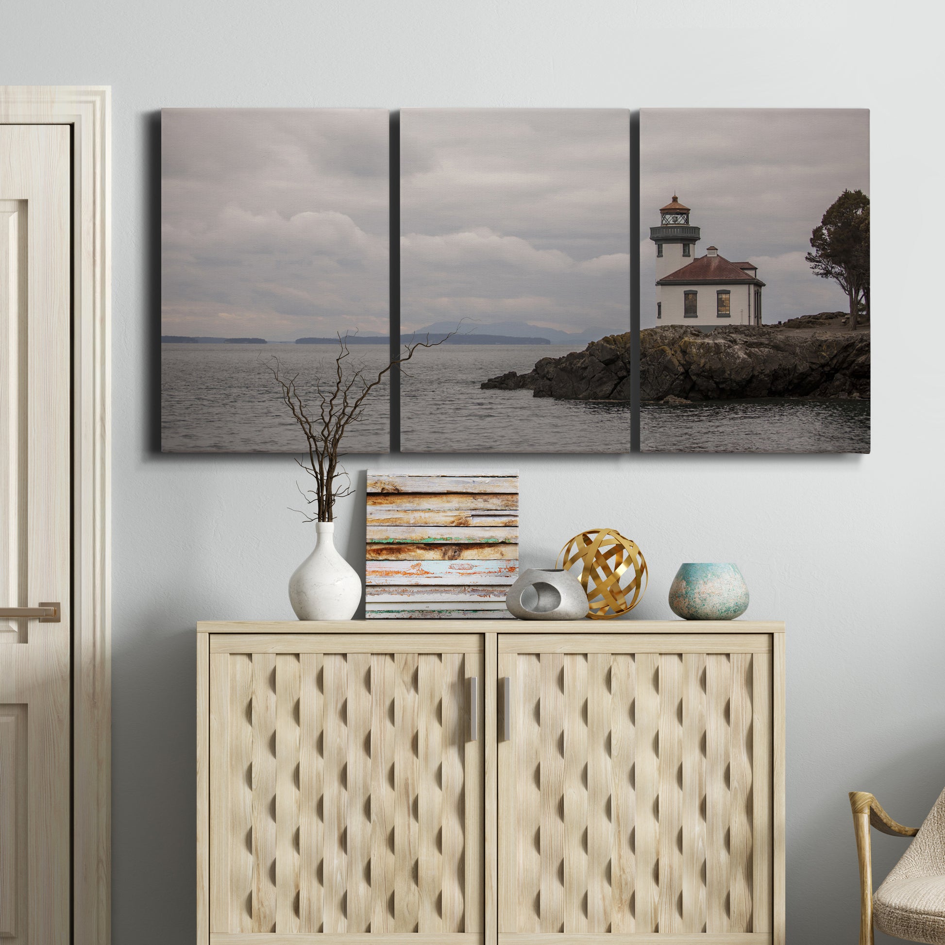 Three-panel canvas wall art featuring lighthouse watching over coastline, displayed above a cabinet in an entryway.