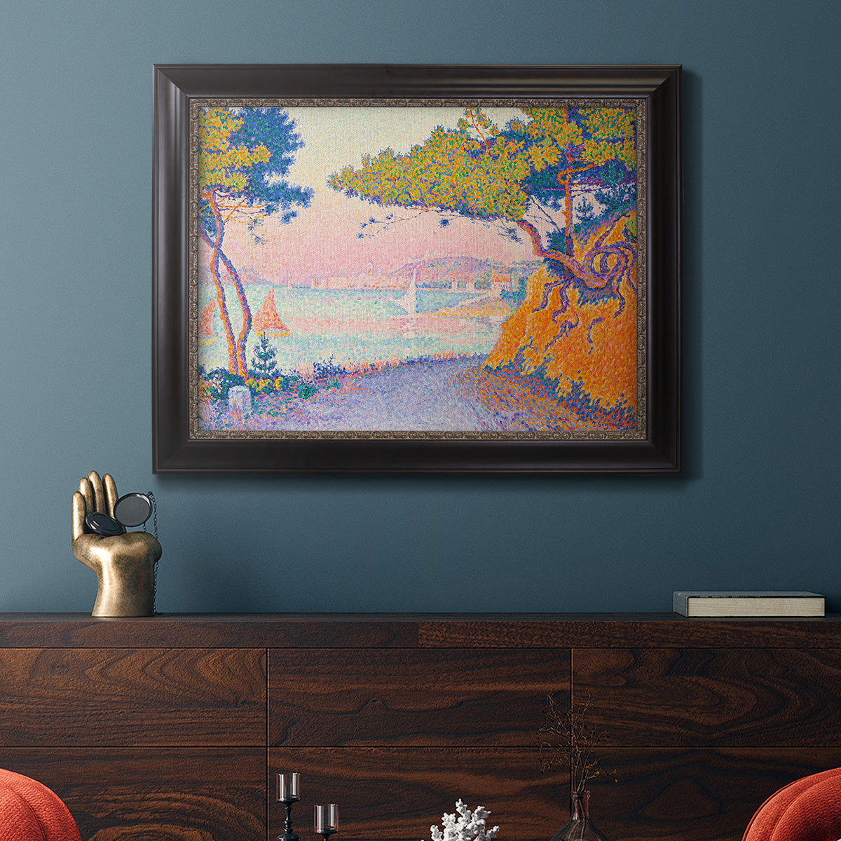 Pointillist coastal seascape by Paul Signac in an ornate black frame with gilded inner detail displayed in a dark-toned interior setting.