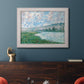 Impressionist river landscape at Vétheuil by Claude Monet in an ornate weathered white frame displayed in a dark-toned interior setting.
