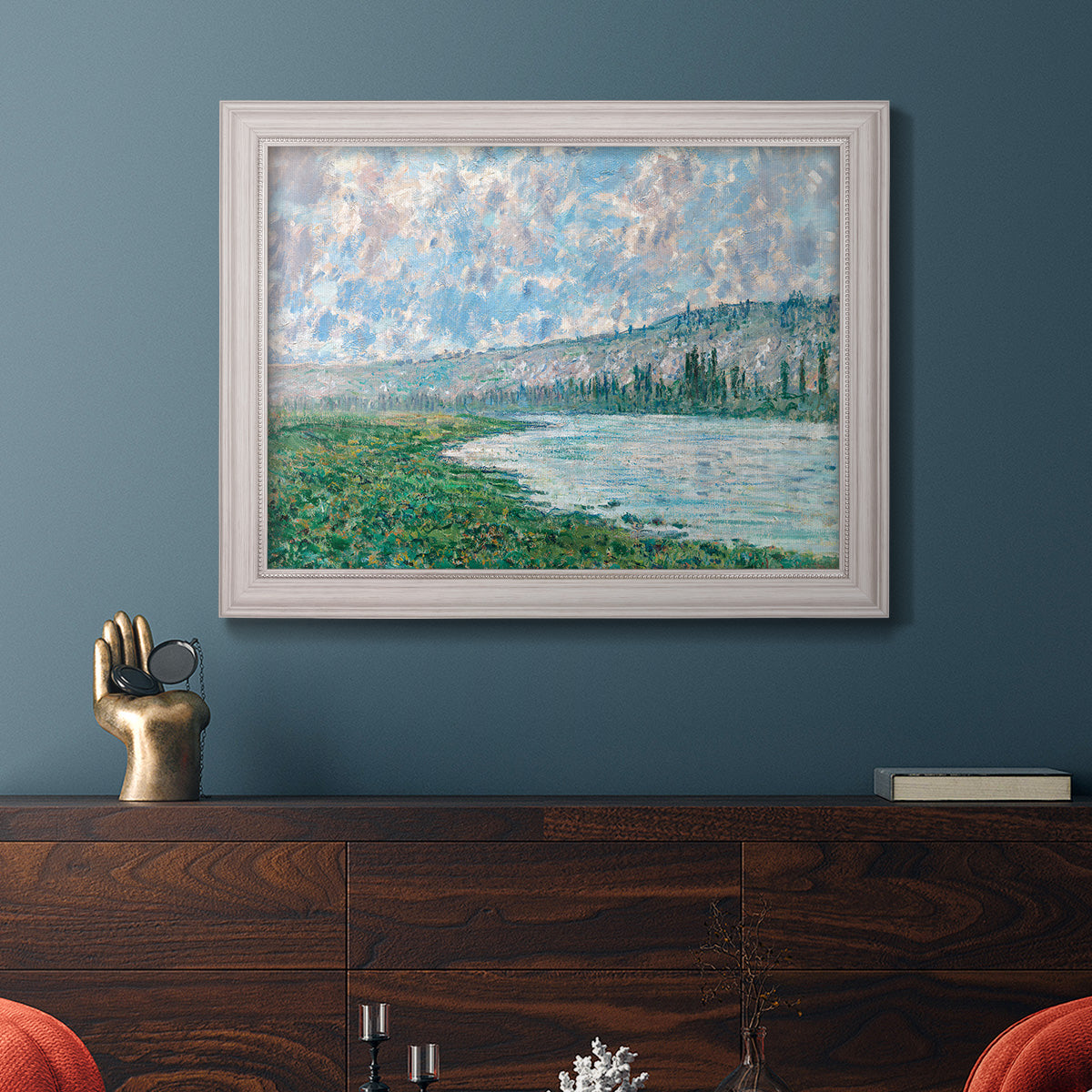 Impressionist river landscape at Vétheuil by Claude Monet in an ornate weathered white frame displayed in a dark-toned interior setting.